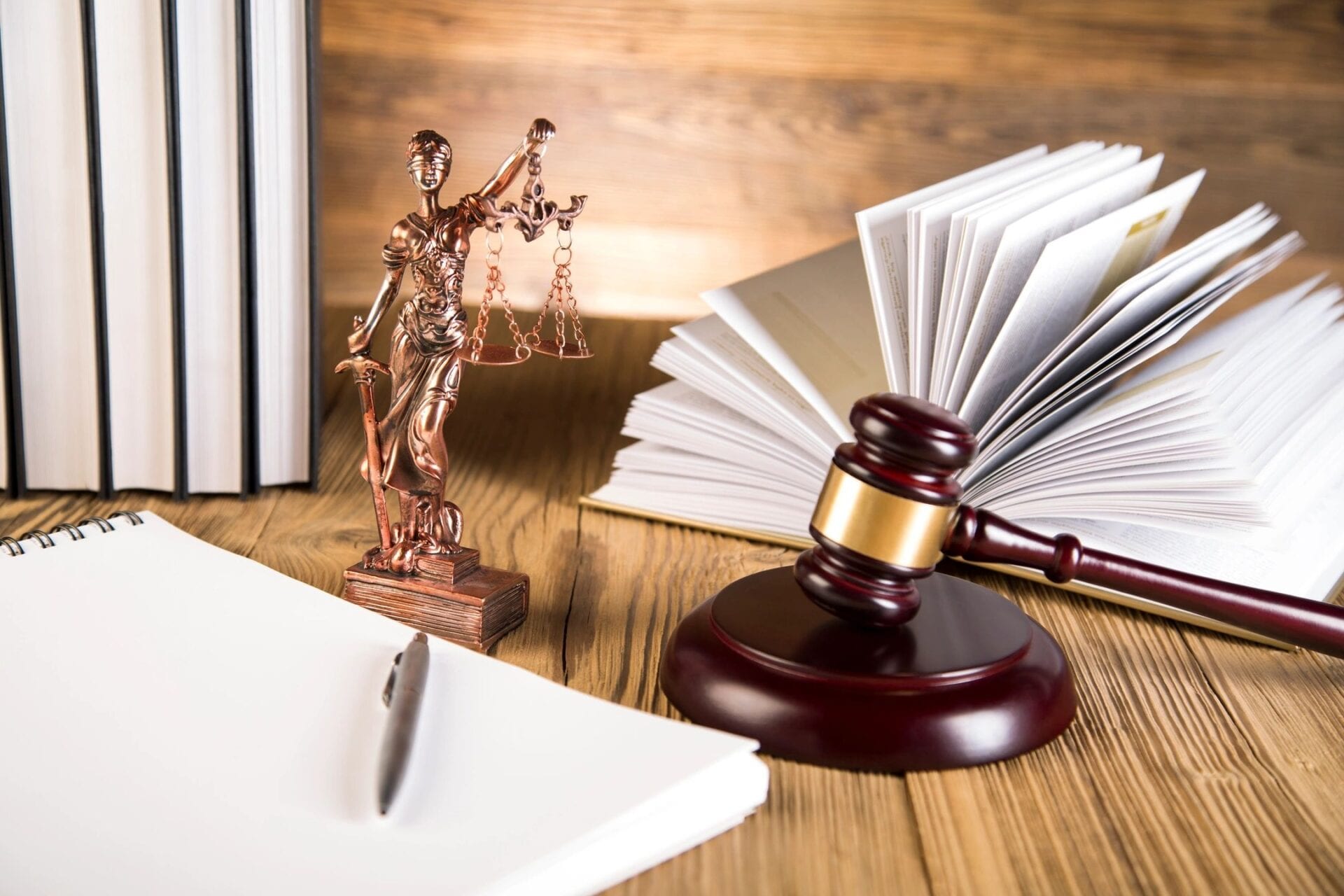 A gavel, statue of justice and books on the table.