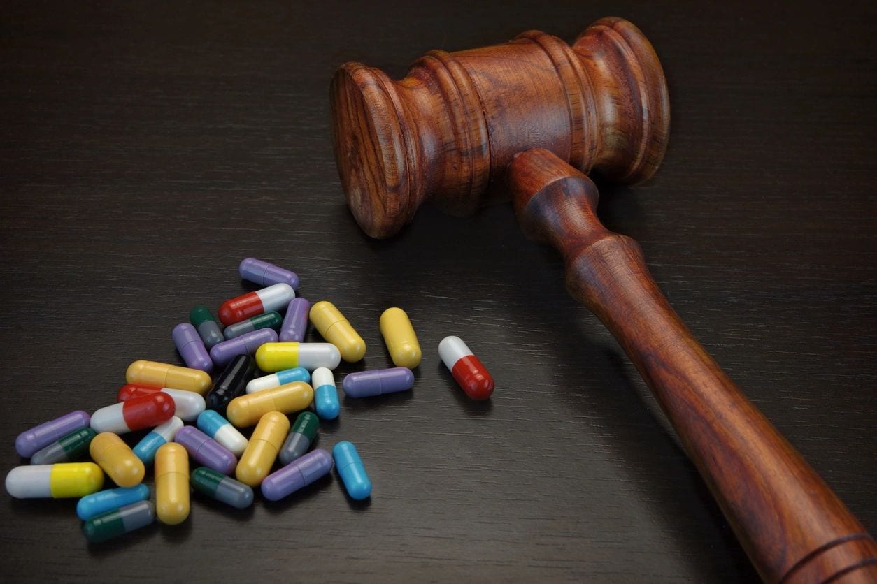 A judge 's gavel and many pills on the table.